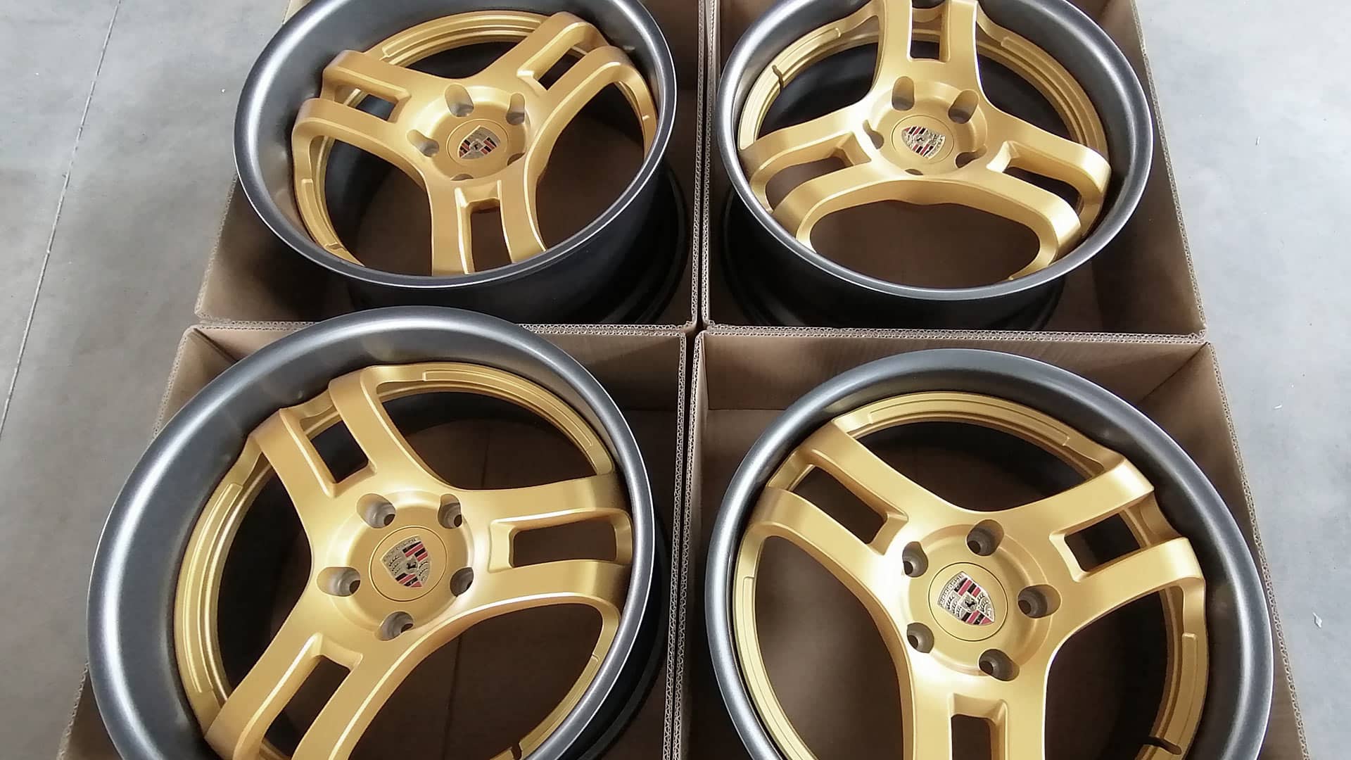 Numerous 19 inch Custom Forged Wheels in 2-piece build with satin gunmetal and satin gold finish sitting on warehouse floor